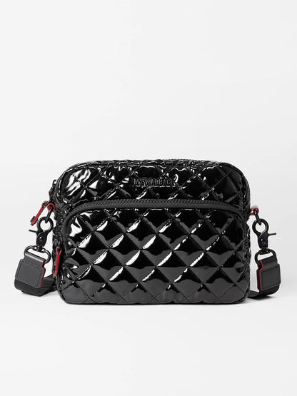 The MZ Wallace Small Metro Camera Bag in Black Lacquer Oxford, showcasing a glossy quilted finish with red accents and an adjustable nylon crossbody strap, is set against a plain white background.