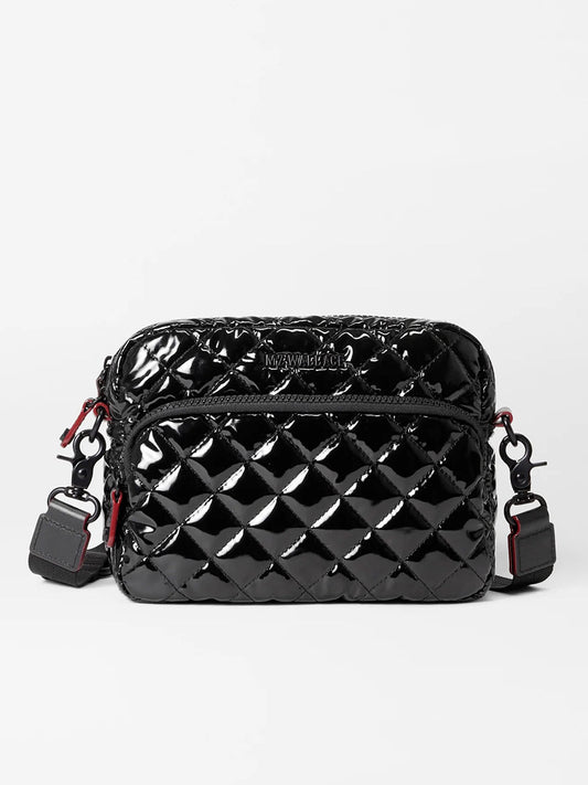 The MZ Wallace Small Metro Camera Bag in Black Lacquer Oxford, showcasing a glossy quilted finish with red accents and an adjustable nylon crossbody strap, is set against a plain white background.