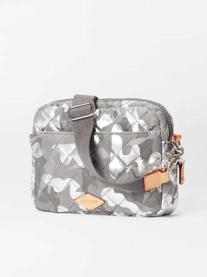 The MZ Wallace Small Metro Camera Bag in Silver Metallic Camo Oxford is a small, quilted gray handbag with silver accents. It features a short strap, zipper closure, and an Italian leather logo tag on the front, all crafted from lightweight nylon for added comfort and convenience.