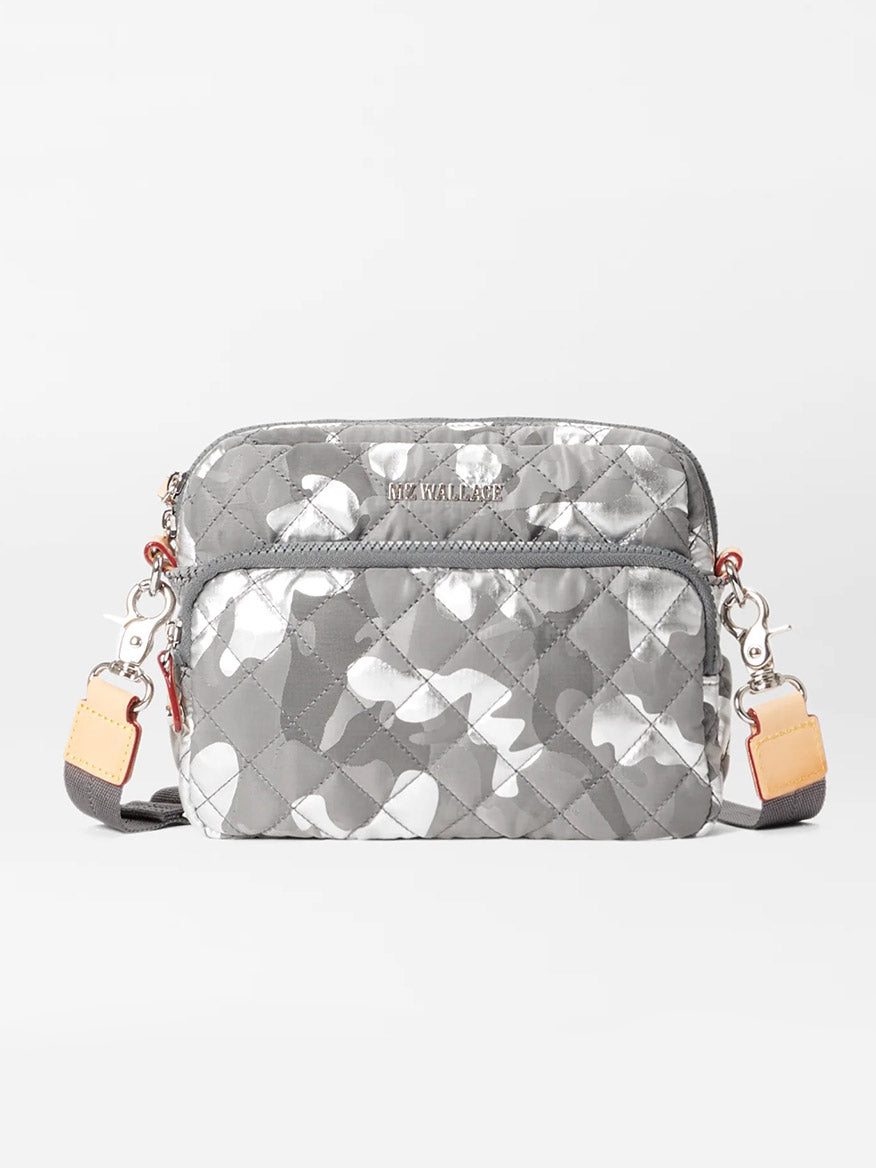 Front view of the MZ Wallace Small Metro Camera Bag in Silver Metallic Camo Oxford with adjustable shoulder straps featuring beige and brown accents, Italian leather trim, and metal clasps on either side.