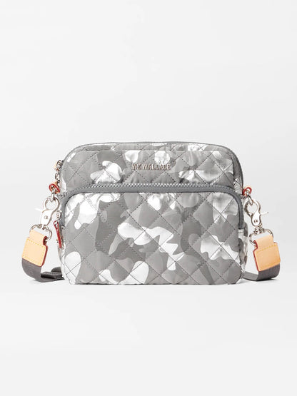 Front view of the MZ Wallace Small Metro Camera Bag in Silver Metallic Camo Oxford with adjustable shoulder straps featuring beige and brown accents, Italian leather trim, and metal clasps on either side.