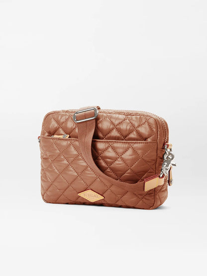 The MZ Wallace Small Metro Camera Bag in Terracotta Oxford features a quilted design, adjustable strap, front pocket, and metal details against a plain background.