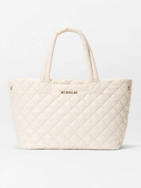 The MZ Wallace Small Metro City Tote in Sandshell Oxford features a quilted cream design, two handles, "MZ WALLACE" gold lettering on the front, and elegant Italian leather trim.