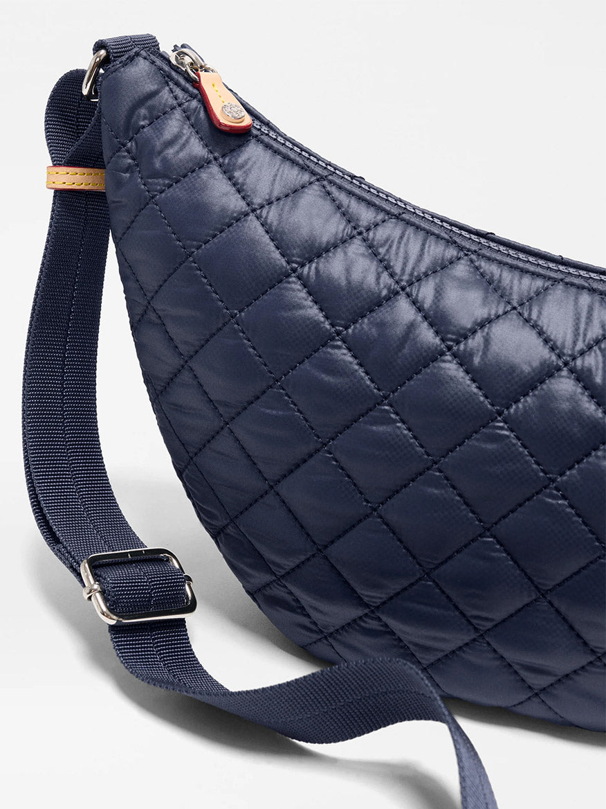 Close-up of the MZ Wallace Small Metro Smile Bag in Dawn Oxford, showcasing quilted navy blue fabric, Italian leather trim, an adjustable nylon strap, and a secure zipper closure.