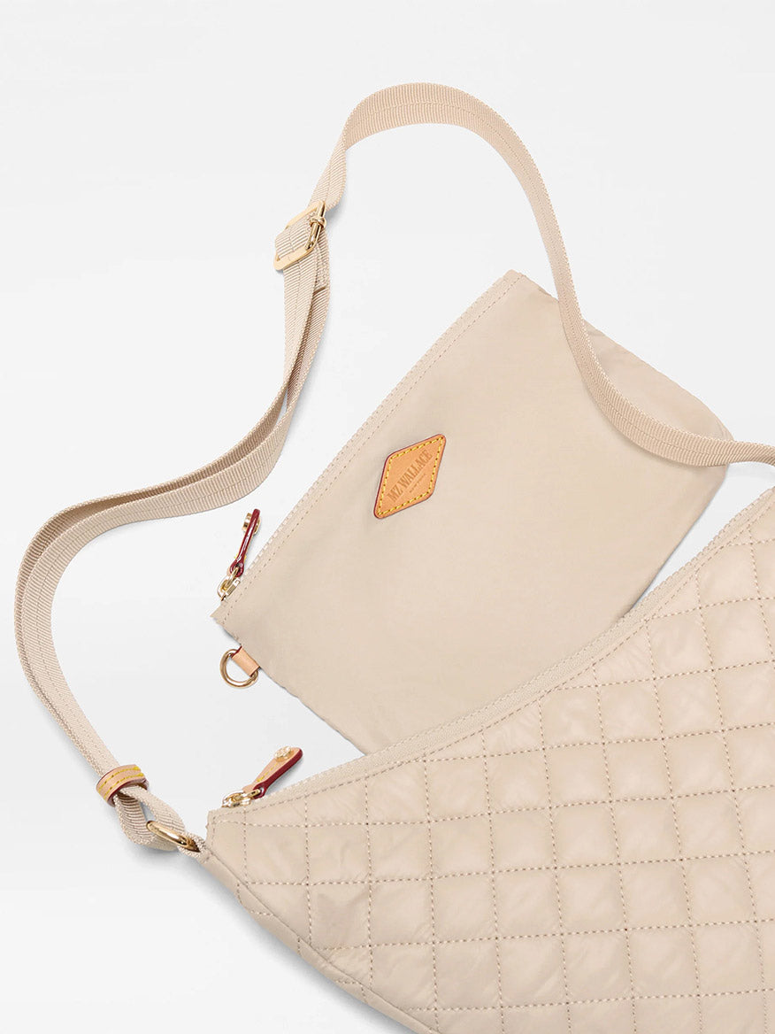 The MZ Wallace Small Metro Smile Bag in Buff Oxford features beige quilted fabric, gold hardware, an adjustable nylon strap, detachable matching pouch, and Italian leather trim, shown on a white background.