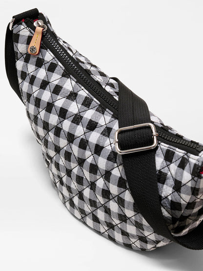 The MZ Wallace Small Metro Smile Bag in Black/White Gingham Oxford features a geometric pattern, adjustable nylon strap, zipper closure, Italian leather trim, and a small tan tag on the zipper.