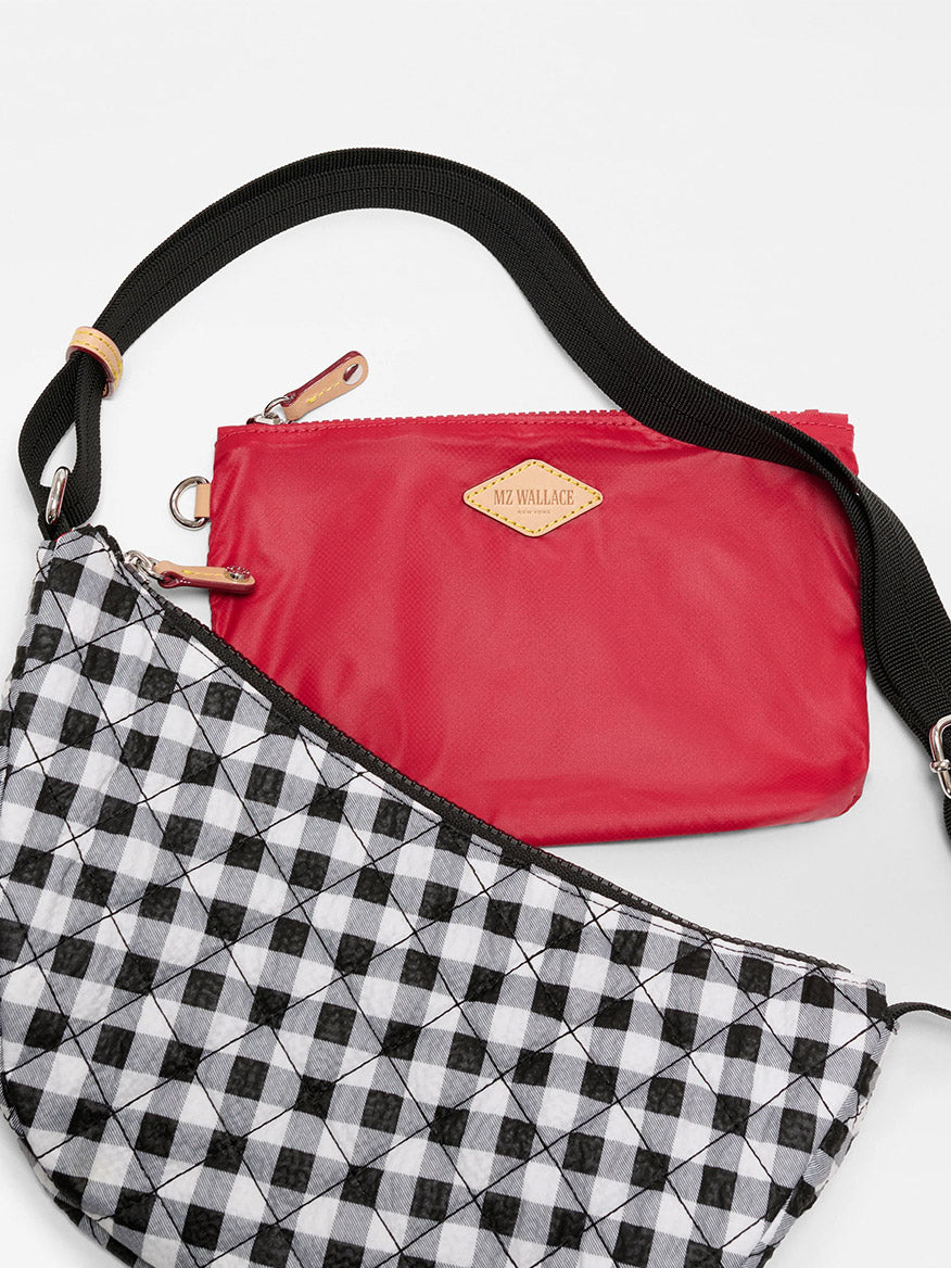 Two bags are shown: one is red with a gold MZ Wallace label and Italian leather trim, the other is the MZ Wallace Small Metro Smile Bag in Black/White Gingham Oxford with a geometric pattern and adjustable nylon strap.