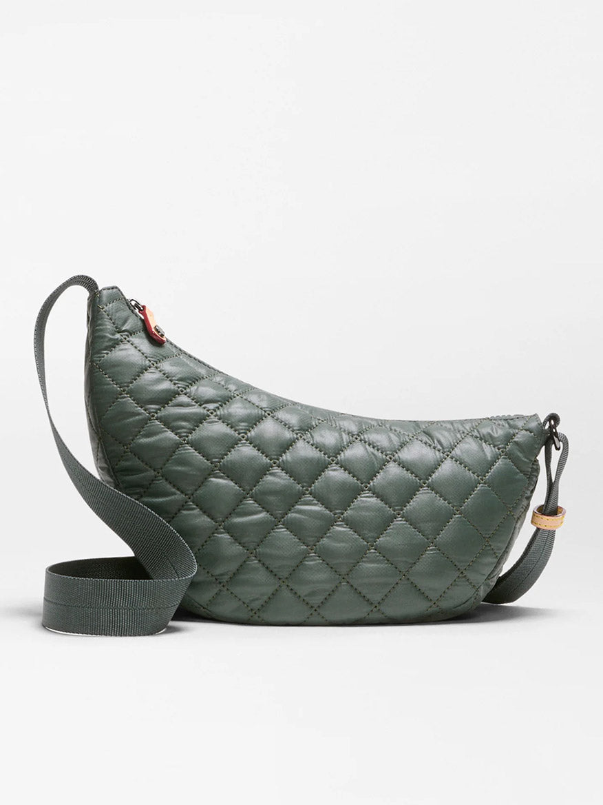 The MZ Wallace Small Metro Smile Bag in Juniper Oxford, a quilted, crescent-shaped green crossbody made from recycled nylon with diamond stitching and a matching adjustable strap, is displayed against a plain white background.