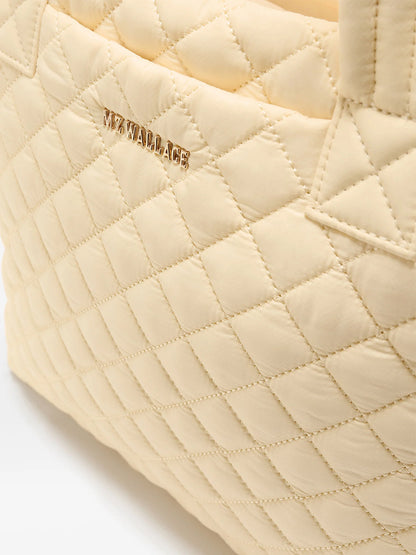 Close-up of the MZ Wallace Small Metro Tote Deluxe in Chamomile Oxford, featuring a quilted finish, gold "MZ WALLACE" logo, and elegant Italian leather trim.