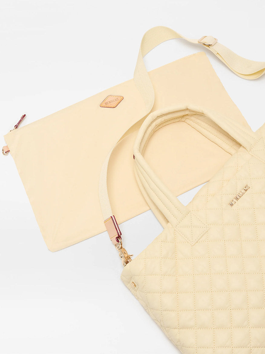 The MZ Wallace Small Metro Tote Deluxe in Chamomile Oxford, featuring Italian leather trim and gold hardware, sits beside a matching zip-top pouch, both displayed on a white background.