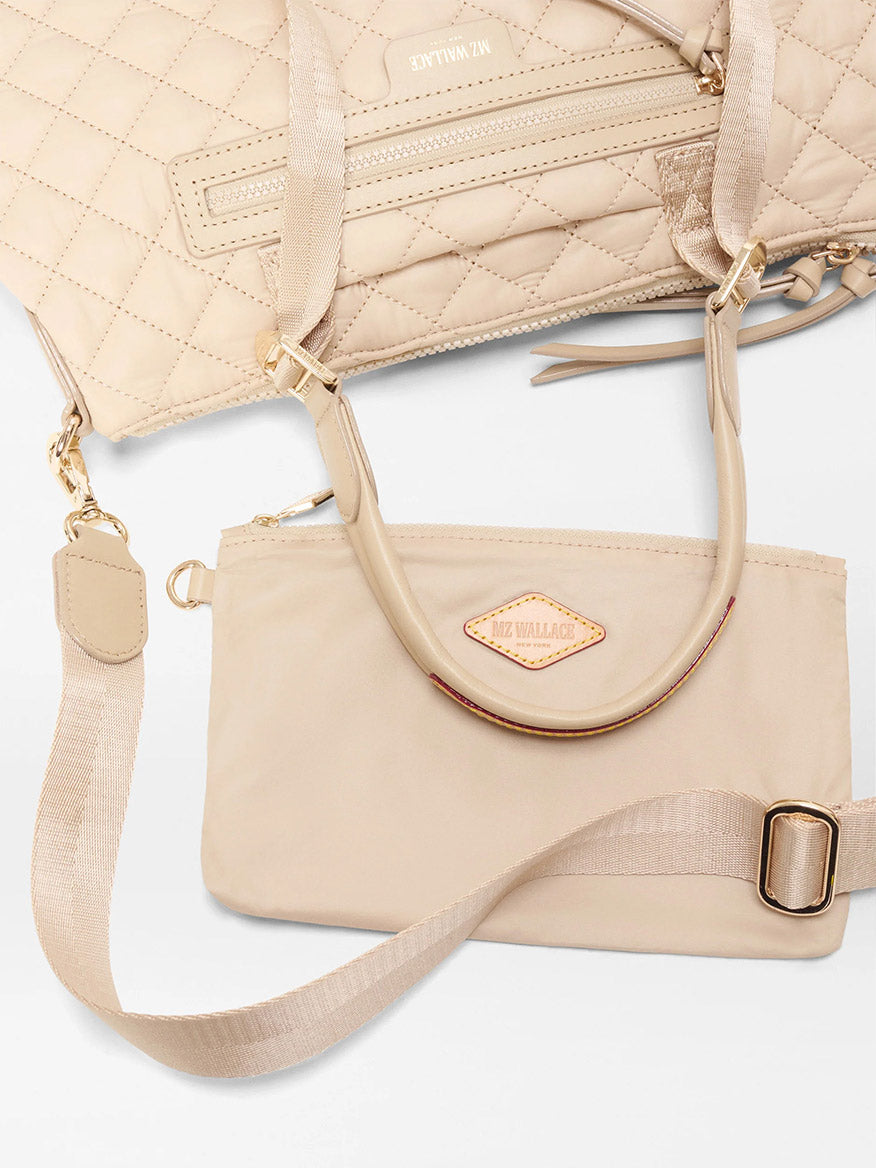 The MZ Wallace Small Park Satchel in Buff Oxford—a beige quilted handbag with gold hardware and Italian leather trim—sits on a white surface, offering an effortless everyday satchel look.
