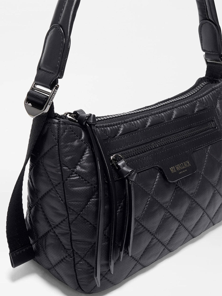 The MZ Wallace Small Park Shoulder Bag in Black Oxford is a lightweight, black quilted crossbody made from Italian leather, featuring a zippered front pocket, tassel accents, and an adjustable strap.
