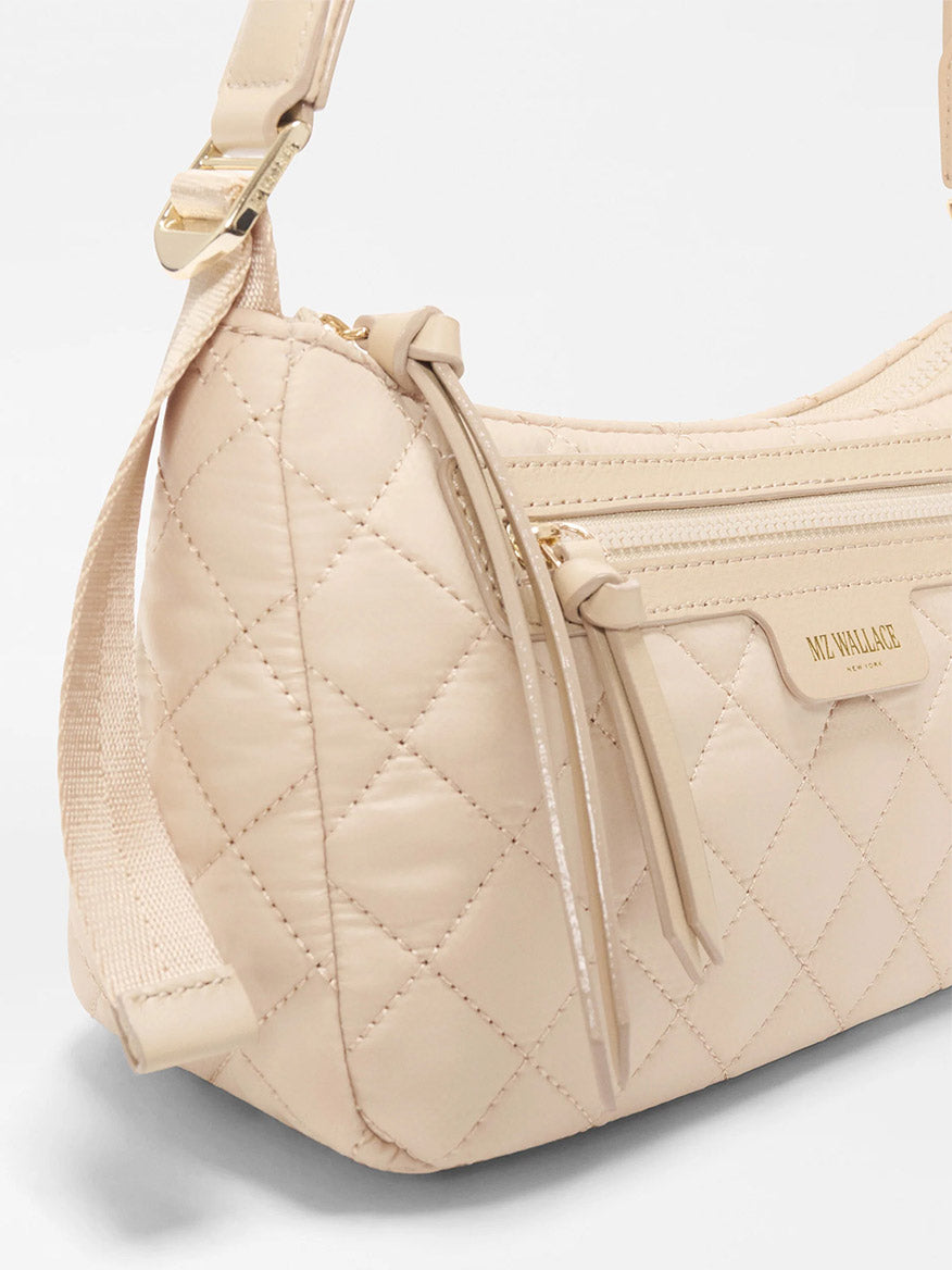 Close-up of the MZ Wallace Small Park Shoulder Bag in Buff Oxford, a lightweight beige quilted purse with a zip pocket, adjustable strap, and gold hardware—perfect for everyday use.