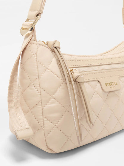 Close-up of the MZ Wallace Small Park Shoulder Bag in Buff Oxford, a lightweight beige quilted purse with a zip pocket, adjustable strap, and gold hardware—perfect for everyday use.