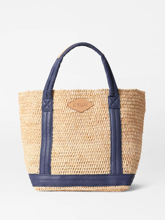 Woven straw MZ Wallace Small Raffia Tote in Raffia/Navy with padded nylon handles and logo patch on the front.