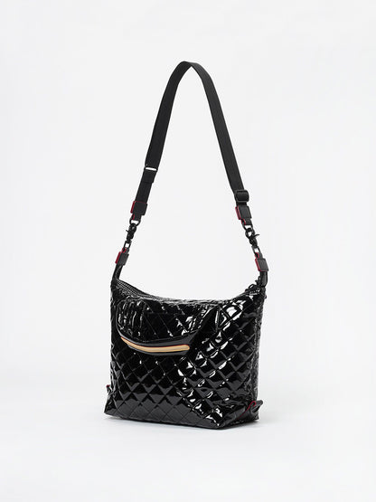 The MZ Wallace Small Sutton Deluxe in Black Lacquer Oxford, featuring a quilted design, front zip pocket, adjustable crossbody strap, shiny patent finish, and Italian leather trim, is displayed against a plain white background.