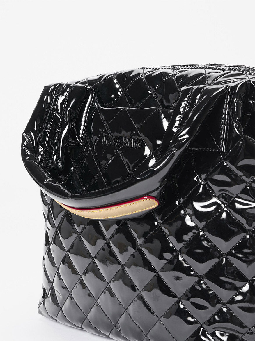 Close-up of the MZ Wallace Small Sutton Deluxe in Black Lacquer Oxford, featuring Italian leather trim, glossy black quilted finish, partially open top, and visible stitching detail.