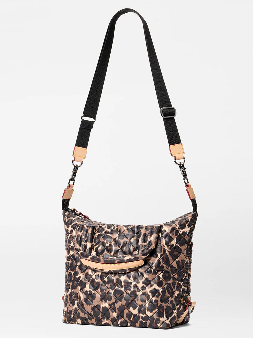 The MZ Wallace Small Sutton Deluxe in Leopard Oxford features a black and beige animal print, adjustable black strap, and tan Italian leather accents, shown against a plain light background.
