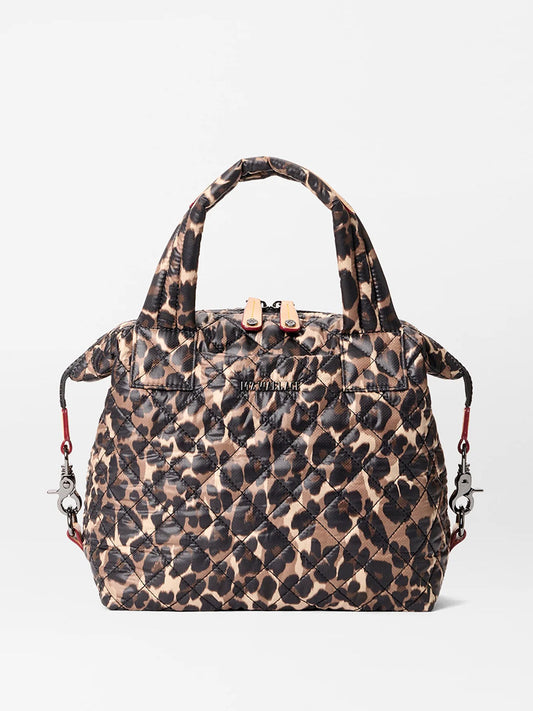 The MZ Wallace Small Sutton Deluxe in Leopard Oxford is a quilted tote with a brown and black leopard pattern, short handles, zipper closure, and detachable shoulder strap clips for crossbody styling.