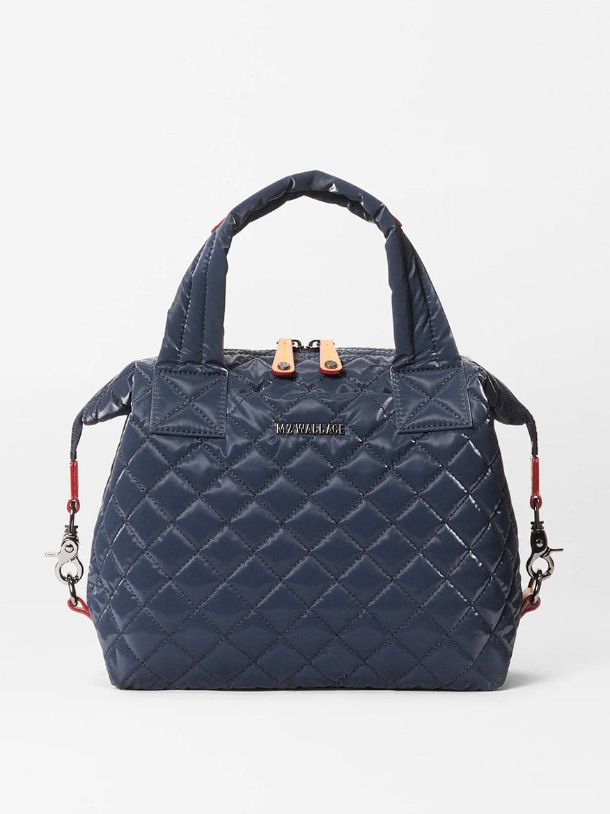 The MZ Wallace Small Sutton Deluxe in Ink Liquid Oxford is a navy blue, quilted handbag with Italian leather trim, short handles, and silver hardware, shown against a plain white background.