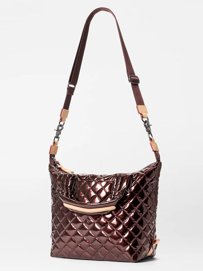 The MZ Wallace Small Sutton Deluxe in Bordeaux Lacquer Oxford is a quilted, shiny dark brown crossbody bag with an adjustable strap, beige accents, Italian leather trim, and a front pocket, shown on a white background.
