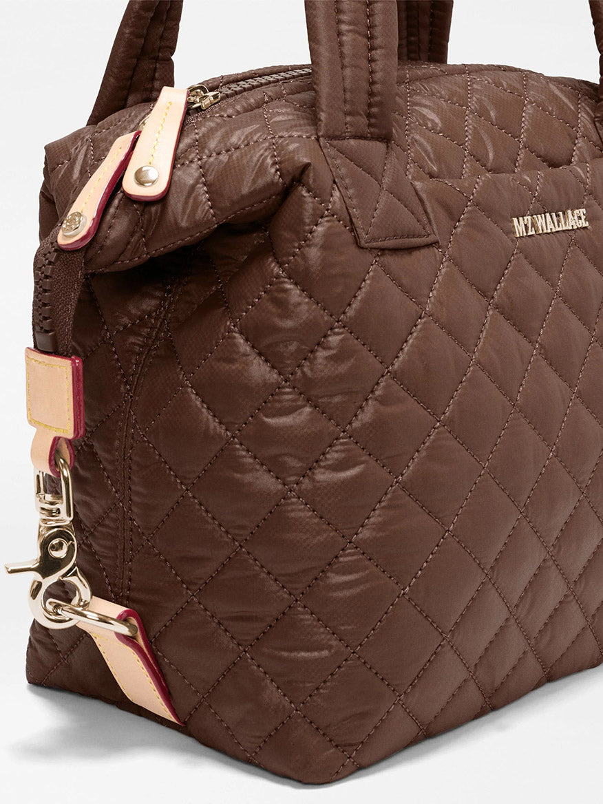 Close-up of the MZ Wallace Small Sutton Deluxe in Walnut Oxford, featuring brown quilted recycled Oxford nylon with gold hardware, beige accents, and the “MZ WALLACE” logo on the side.