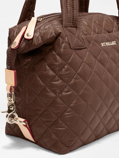 Close-up of the MZ Wallace Small Sutton Deluxe in Walnut Oxford, featuring brown quilted recycled Oxford nylon with gold hardware, beige accents, and the “MZ WALLACE” logo on the side.