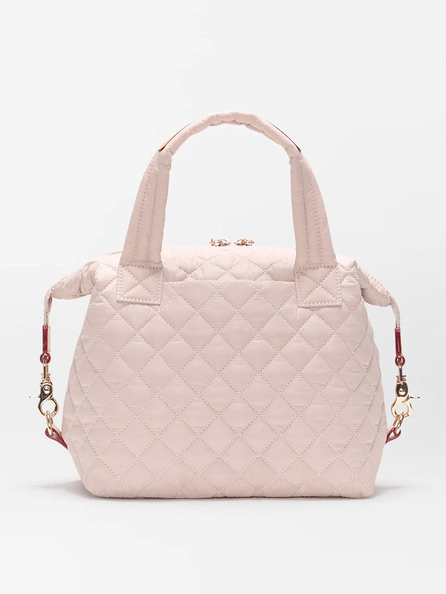 The MZ Wallace Small Sutton Deluxe in City Pink Oxford is a quilted nylon bag with two short handles, gold hardware, and detachable side straps, displayed on a plain white background.