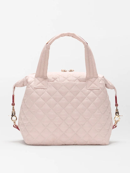 The MZ Wallace Small Sutton Deluxe in City Pink Oxford is a quilted nylon bag with two short handles, gold hardware, and detachable side straps, displayed on a plain white background.