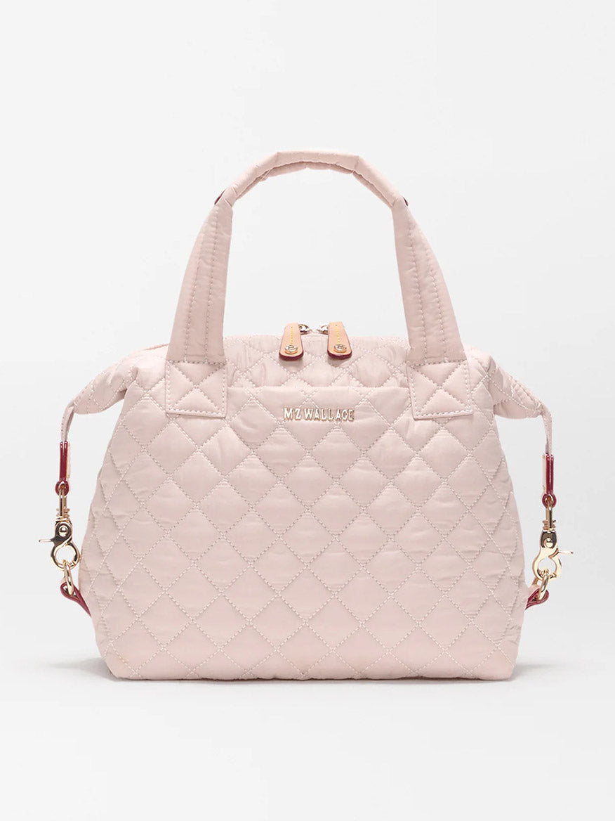 The MZ Wallace Small Sutton Deluxe in City Pink Oxford features quilted nylon, top handles, a zip closure, detachable adjustable crossbody strap, and gold-tone hardware, shown against a plain white background.