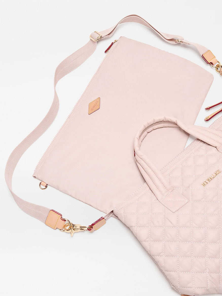 Two pale pink quilted nylon MZ Wallace Small Sutton Deluxe bags in City Pink Oxford are shown: one has an adjustable crossbody strap, and the other is a tote with short handles and gold-tone hardware.