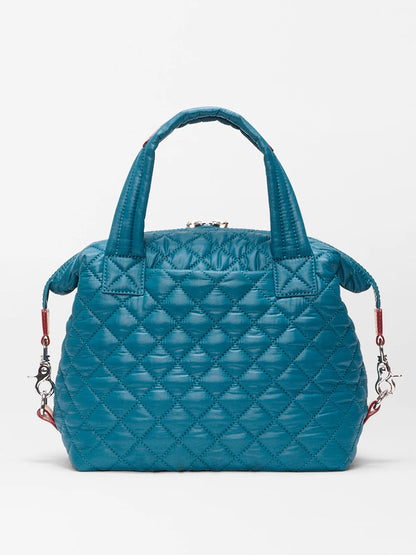 The MZ Wallace Small Sutton Deluxe in Pacific Oxford is a teal quilted nylon bag with short handles, a detachable adjustable crossbody strap, silver hardware, and red accent loops—stylish and versatile.