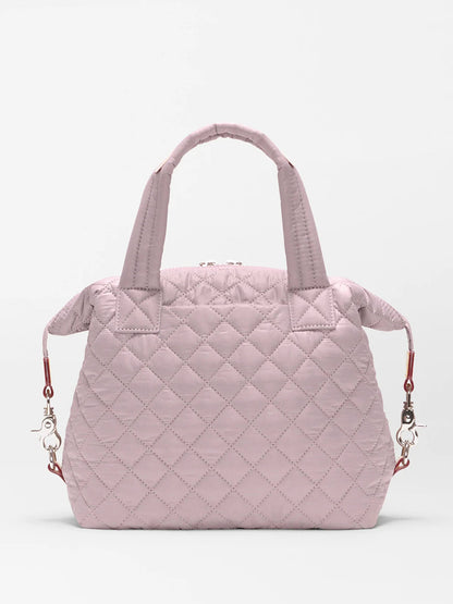 The MZ Wallace Small Sutton Deluxe in Quail Oxford is a light pink quilted convertible tote crossbody with two short handles and detachable shoulder straps, shown against a plain white background.