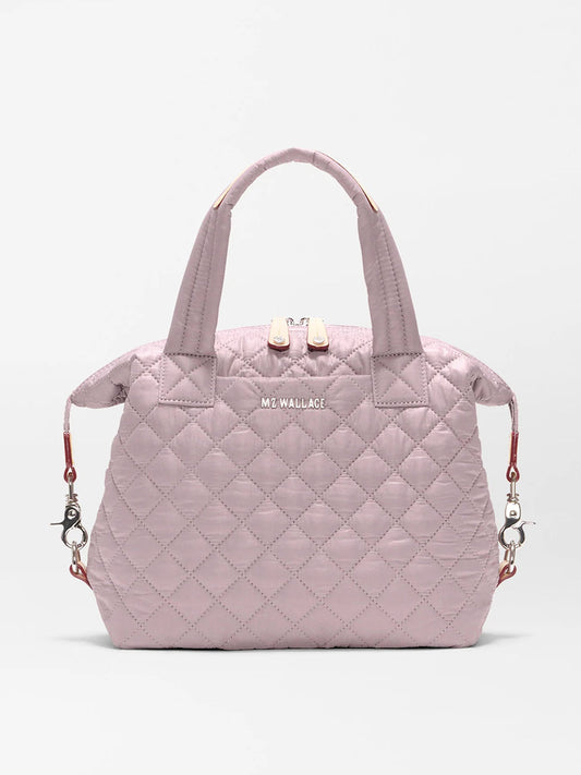 The MZ Wallace Small Sutton Deluxe in Quail Oxford is a light pink quilted recycled nylon bag with two handles, zippered top, detachable shoulder strap for tote or crossbody wear, and features the "MZ WALLACE" logo on the front.