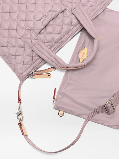 The MZ Wallace Small Sutton Deluxe in Quail Oxford is a quilted mauve recycled nylon bag with zipper closure, detachable shoulder strap, and stitched handles, shown laid flat on a white background.