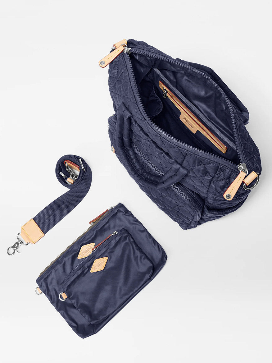 A MZ Wallace Small Utility Backpack in Dawn Oxford made from recycled oxford with an open top, showing its interior compartments, fits a 14" laptop, and is accompanied by a matching smaller pouch and a detachable strap.