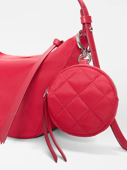 The MZ Wallace Small Waverly Hobo in Apple Bedford is a red handbag with silver hardware, a zip top closure, and a quilted round coin purse attached to its strap.