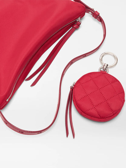 The MZ Wallace Small Waverly Hobo in Apple Bedford is a red Italian leather bag with a zip closure and a matching quilted round coin pouch, both featuring leather zip pulls and joined by a metal key ring.