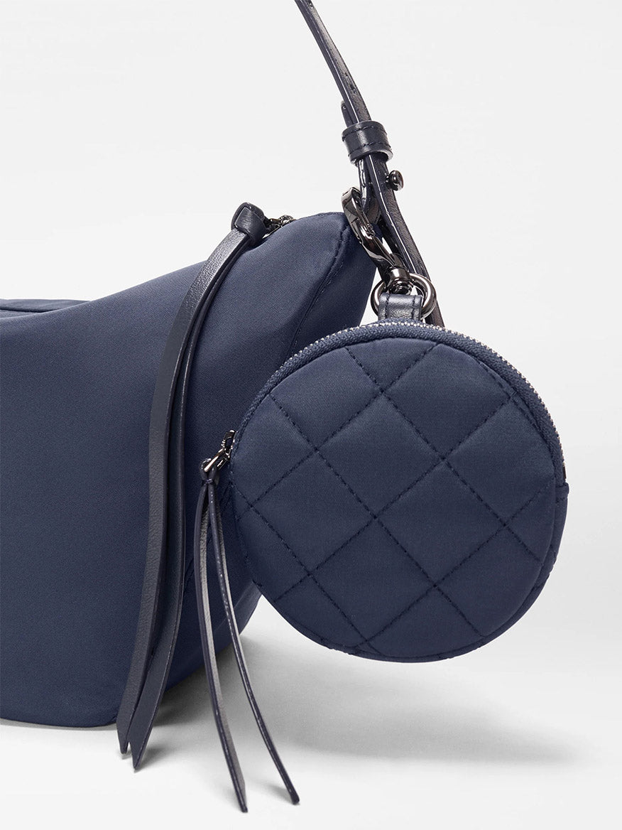 Close-up of the MZ Wallace Small Waverly Hobo in Dawn Bedford, featuring a quilted navy Italian leather round coin purse attached to the bag with a leather strap and zip top closure, set against a plain background.