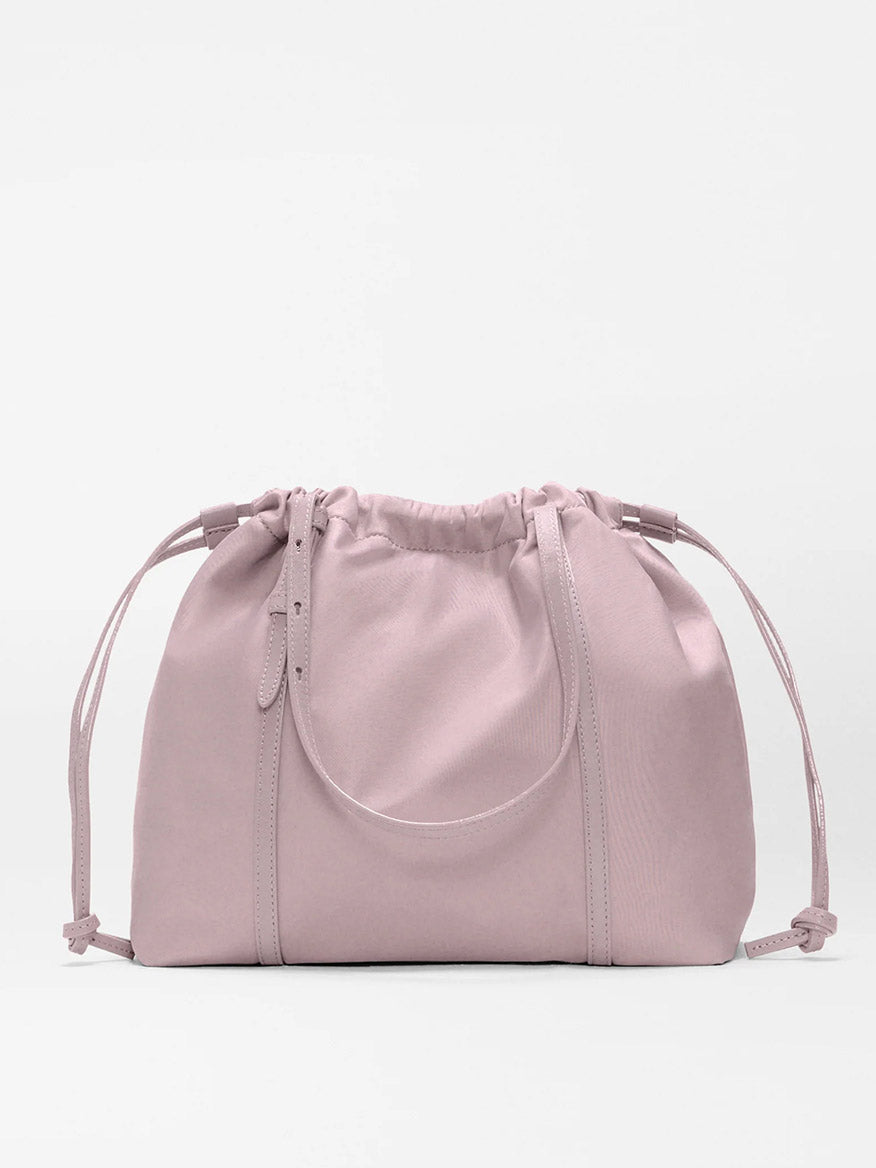 The MZ Wallace Small Waverly Tote in Quail Bedford is a light pink drawstring bag with short handles, made from recycled nylon and detailed with Italian leather trim, shown on a plain white background.