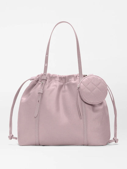 The MZ Wallace Small Waverly Tote in Quail Bedford features recycled nylon, Italian leather trim, adjustable shoulder straps, drawstring sides, and a small round zippered pouch on the front.