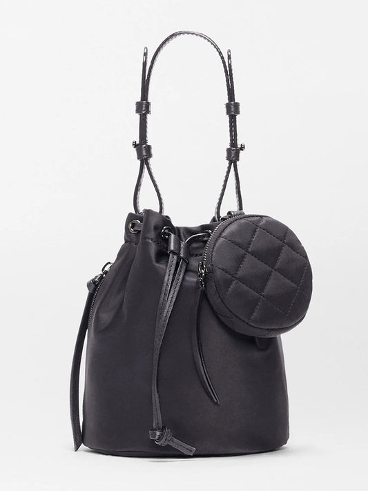 The MZ Wallace Waverly Bucket Bag in Black Bedford features a drawstring closure, shoulder straps, Italian leather trim, and a small round quilted pouch on the front, showcased against a plain light background.