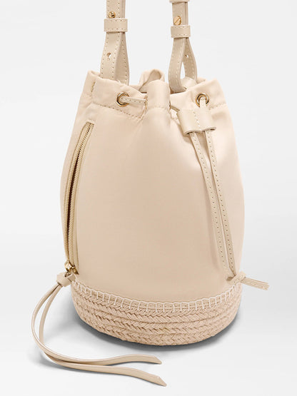 The MZ Wallace Waverly Espadrille Bucket Bag in Buff Bedford features a beige finish, drawstring closure, gold hardware, Italian leather trim, side zipper pocket, beige lining, and a braided woven espadrille base.