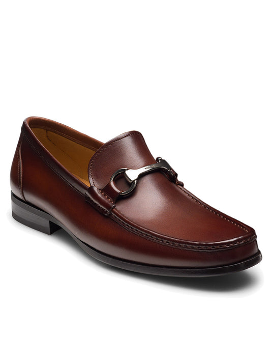 The Magnanni Gentry in Cognac is a brown supple leather loafer with a decorative metal buckle on the upper, featuring a smooth finish and low heel, evoking the classic bit loafer style.