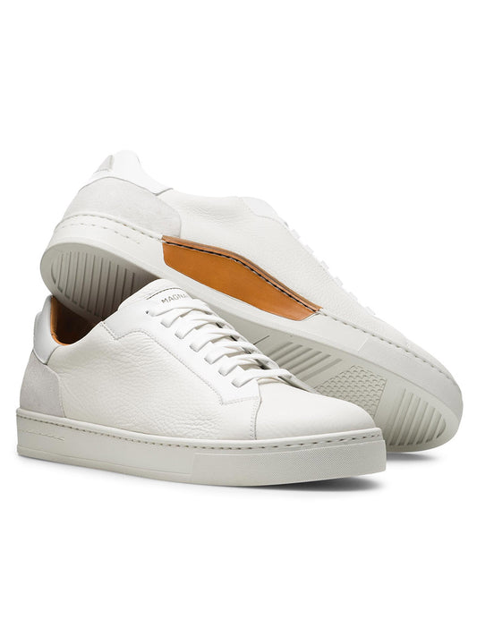 Two Magnanni Amadeo sneakers, made in Spain, feature white leather with textured surfaces and an orange inner lining. The left shoe stands upright, while the right reveals its intricate sole pattern—a contemporary luxury sneaker masterpiece.