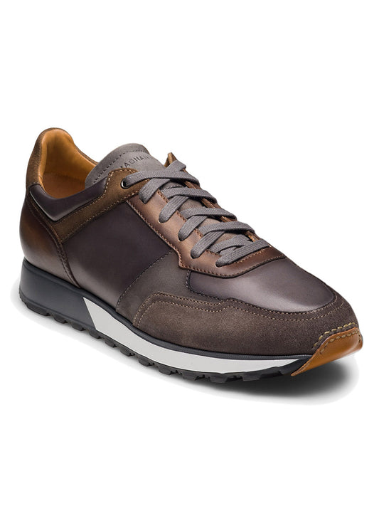 The Magnanni Arco in Grey & Brown is a hand-stitched leather sneaker featuring gray laces, tan accents, and a black rubber sole. Displayed at an angle on a white background, this retro sport shoe blends expert craftsmanship with timeless style.