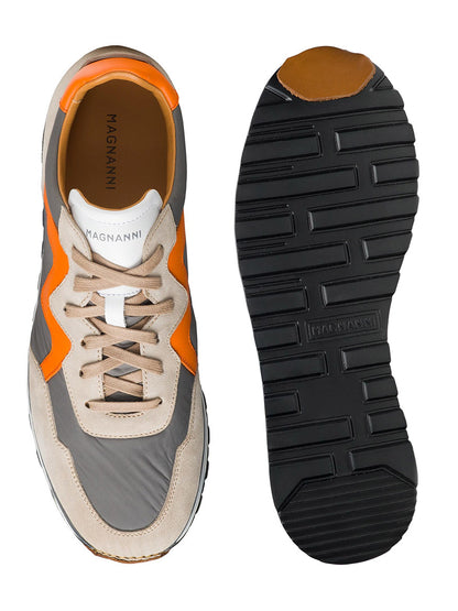 The Magnanni Asher in Grey/Orange is a pair of sporty sneakers shown from the side and bottom, featuring light tan, orange, and gray accents with black rubber outsoles. The insole proudly displays the brand "Magnanni.