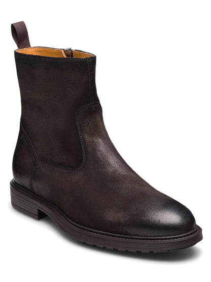 The Magnanni Atlas Zip in Waxed Brown Suede, a single men’s dark brown suede ankle boot handmade in Portugal, featuring a side zipper, low heel, and back pull tab, is shown at a three-quarter angle on a white background.