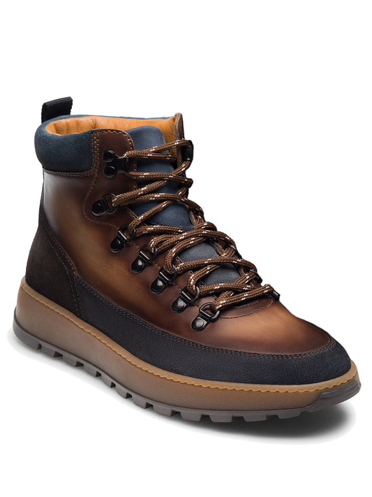The Magnanni Borazo in Indigo/Brown is a leather hiker boot featuring dark laces, a padded ankle collar, and a thick ridged rubber sole for rugged functionality. Shown at an angle to display both the front and side views.