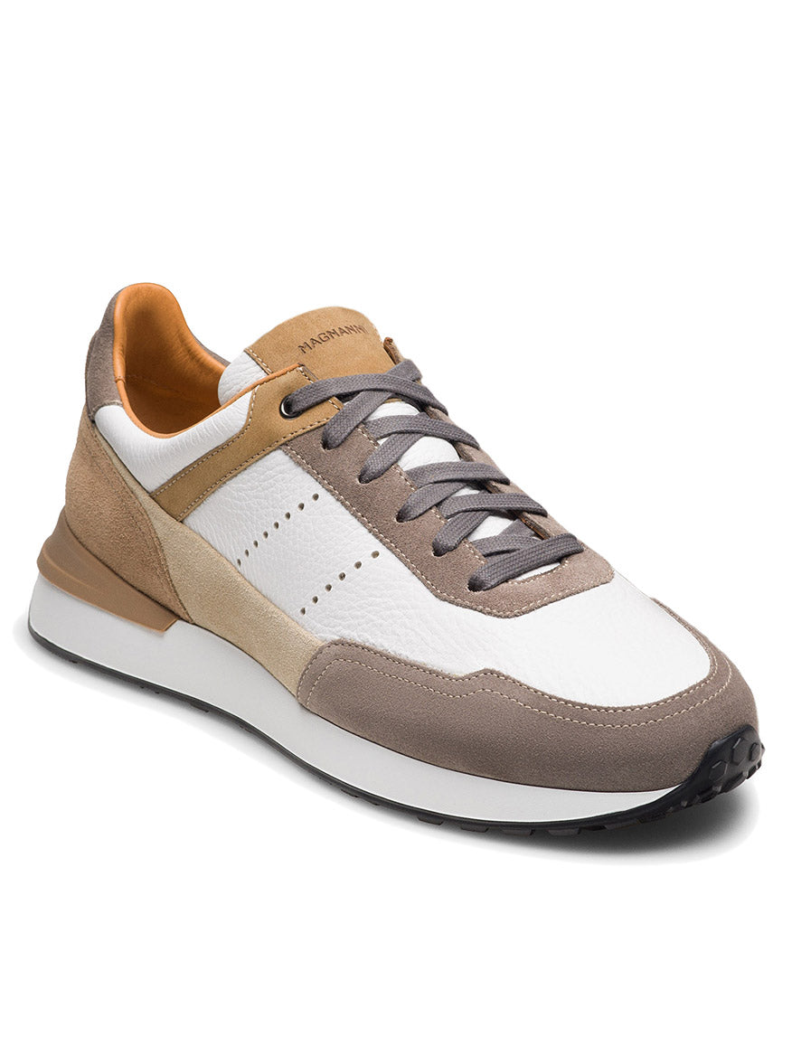 The Magnanni Bravo V in Taupe Suede & White is a luxury men's low-top sneaker with white, beige, and brown panels, gray laces, a white midsole, and a black outsole.